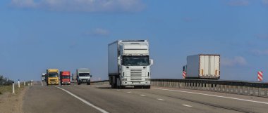 Kamyonlar karşı istikamette bir banliyö otoyolu boyunca ilerliyor.