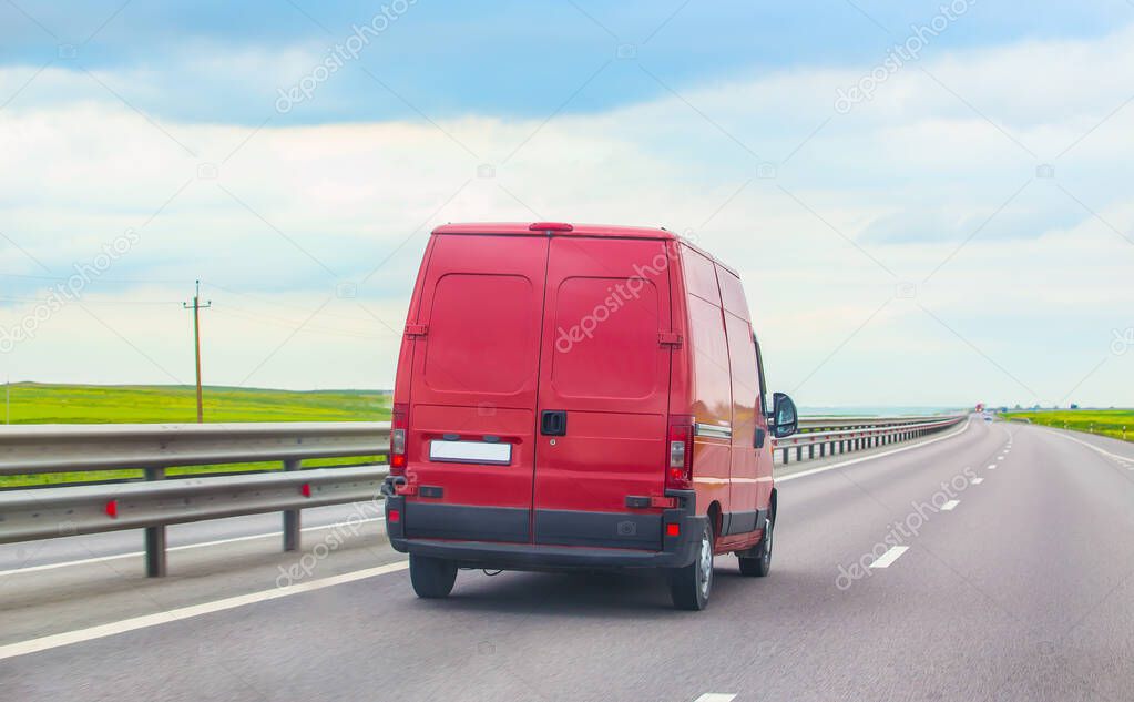 Red minibus moves along a suburban highway
