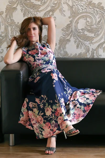 Mulher de vestido com estampa de flores no sofá — Fotografia de Stock