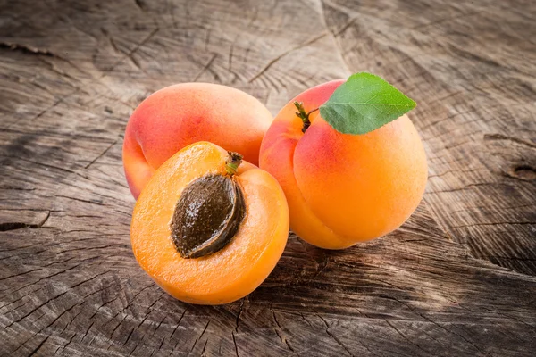 Apricots with leaves on wooden background — Stock Photo, Image