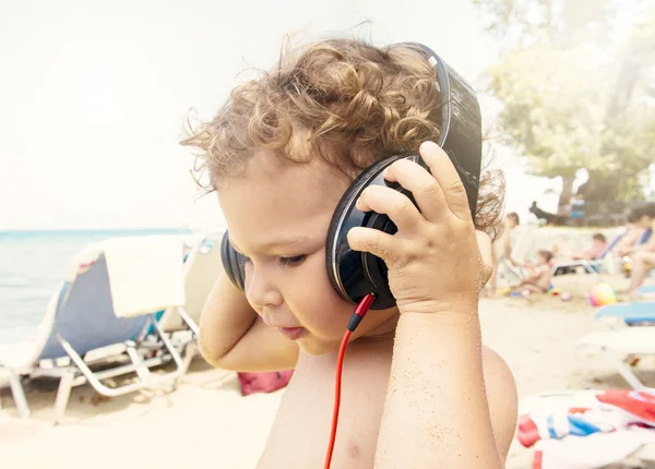 Criança ouve música na praia — Fotografia de Stock