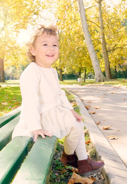 Ребенок сидит на скамейке в парке — стоковое фото