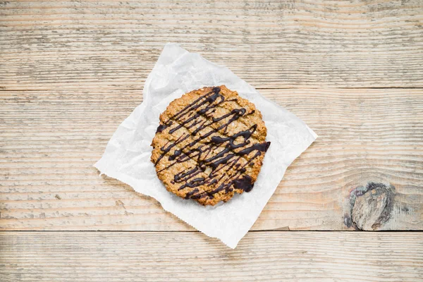 Oatmeal cookie topped with chocolate on wooden table. Top view — Stock Photo, Image