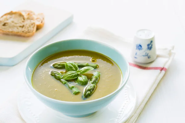 Asparagus soup in a bowl topped with fresh basil — Stock Photo, Image