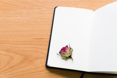 Açık defter kopya alanı ile ahşap masa üzerinde kuru gül ile