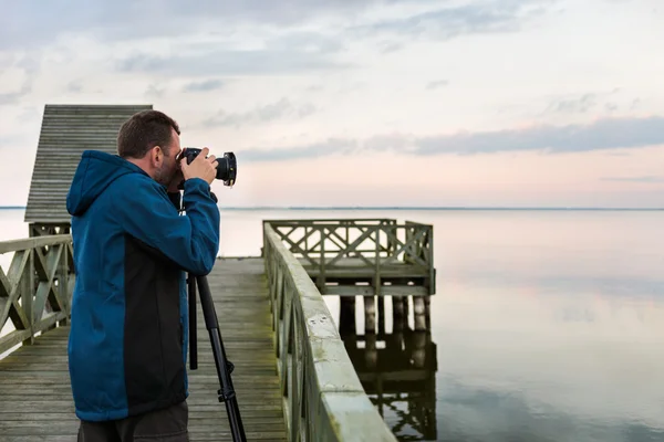 Fotógrafo da natureza tirando fotos do lago ao pôr do sol — Fotografia de Stock