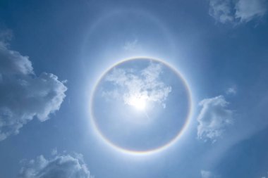 Güneş koronası gökkuşağı bulutları ve mavi gökyüzü arkaplanı, çevresindeki haleler.