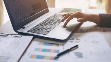 Ofiste dizüstü bilgisayarla çalışan iş adamları, dizüstü bilgisayarlar ve ahşap masa üzerindeki iş belgeleri, iş konsepti