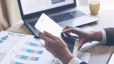 İş adamlarının elini kapatıyoruz. Tablet telefon kullanıyoruz. Akıllı telefon, belgeler, dizüstü bilgisayar, iş konsepti.