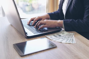 Ofiste dizüstü bilgisayarla çalışan iş adamları, dizüstü bilgisayar ve ahşap masada Amerikan Doları faturası, iş konsepti.