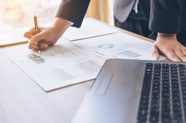 Toplantıda iş belgesine işaret eden iş adamlarının resmi, ahşap masadaki defter