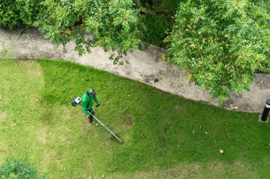 Çim biçme makinesiyle çim biçen bir işçi.