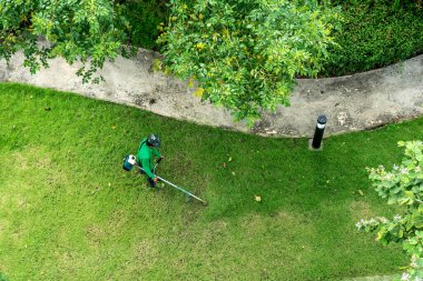 Çim biçme makinesiyle çim biçen bir işçi.