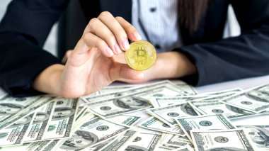 İş adamı zengini tüccar Bitcoin altın sikkesi tutuyor Bitcoin tüccarı için yeni para değişimi ve masa başı iş konsepti üzerine Amerikan doları banknotları
