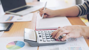 Yıllık gelir vergisi ve şirket gelir hesaplamasını hesaplayan hesap makinesiyle çalışan muhasebecinin elini kapat - iş konsepti
