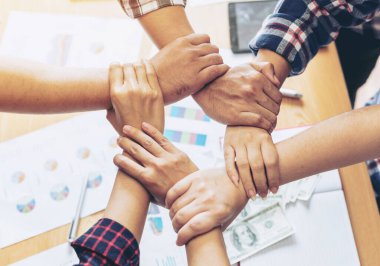 İş ortaklıklarının kapanışı insanlar el ele tutuşup ofis masasında birlik ve takım çalışması kavramını göstererek toplantılarını bitirdiler.