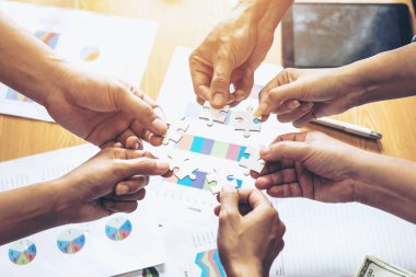 Grup iş ortaklarının eli kapanıyor. İnsanlar yapboz, iş ekibi stratejisi kavramını bir araya getiriyorlar.