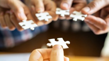 Grup iş ortaklarının eli kapanıyor. İnsanlar yapboz, iş ekibi stratejisi kavramını bir araya getiriyorlar.