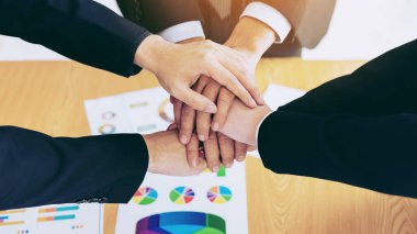 İş ortaklığının kapanışı. İnsanlar el ele tutuşup toplantıyı bitiriyor. Ofis masası üzerinde birlik ve iş birliği gösteriyorlar.