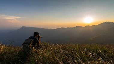 Günbatımında bir uçurumun tepesinde duran gezgin fotoğrafçı gün batımında Tayland manzarası