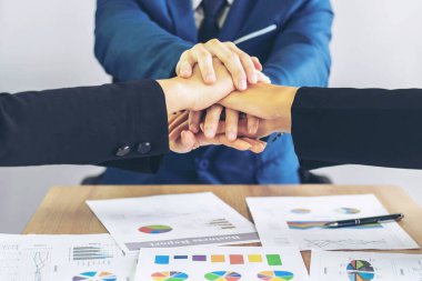 İş ortaklığının kapanışı. İnsanlar el ele tutuşup toplantıyı bitiriyor. Ofis masası üzerinde birlik ve iş birliği gösteriyorlar.