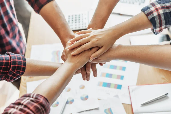 close up hand of business partnership people stacking hands finishing up meeting showing unity over office desk  , business teamwork concept