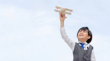 Mavi gökyüzü arka planında pilot olmayı hayal eden havacı oyuncak uçak hayal gücü oynayan genç çocuk. 