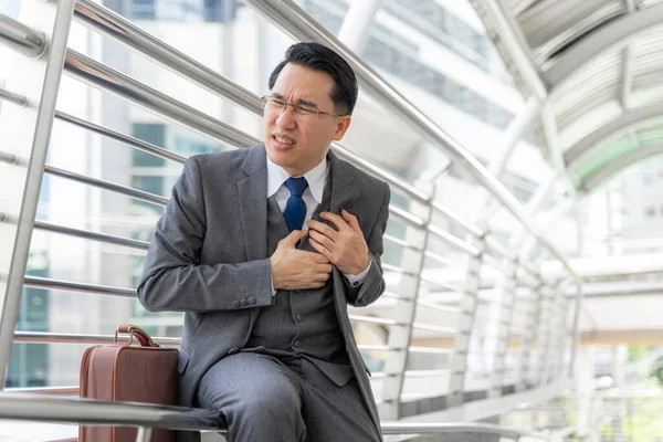 asian businessman suffering from bad pain in his chest heart attack -  business people heart disease concept