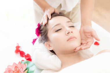 Güzel ve sağlıklı genç bir kadın güzellik salonunda yüz masajıyla rahatlıyor.