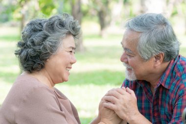 Happy love Elderly couple smile face , Senior couple old man and senior woman relax holding hands in a forest