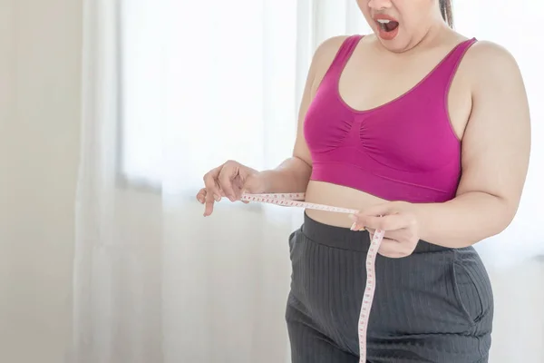 asian fat women , Fat girl , Chubby, overweight measuring her waist in the bedroom - Woman diet lifestyle overweight problem concept