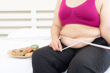 Asyalı şişman kadınlar, şişman kız, tombul, kilolu, ölçü bandıyla kilolu, yanında tatlı bir pasta - kadın diyeti yaşam tarzı aşırı kilolu problem konsepti