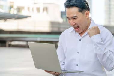 İş dünyasından Asyalı bir adam iş bölgesi kentlerinde dizüstü bilgisayar kullanıyor - iş adamları kavramı