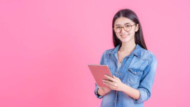 Güzel, sevimli Asyalı kadın pembe arka planda akıllı telefon tableti bilgisayarını oynuyor - yaşam tarzı kadın konsepti