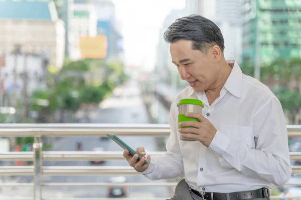 成功的亚洲商人手里拿着智能手机和咖啡杯 商业理念 — 图库照片