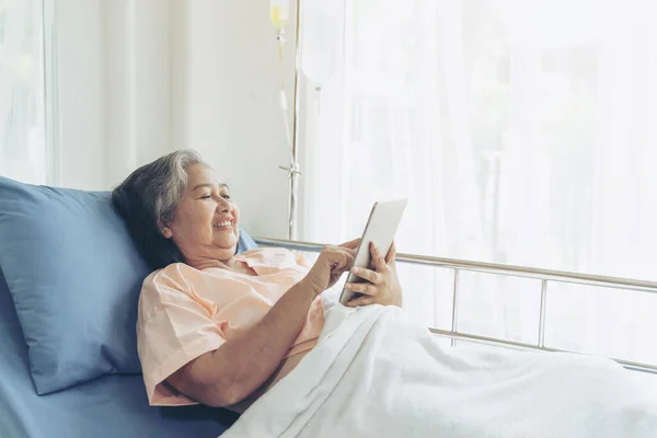 Elderly senior woman patients in hospital bed patients using smart phone call to descendant relatives feel happiness - senior female medical and healthcare concept