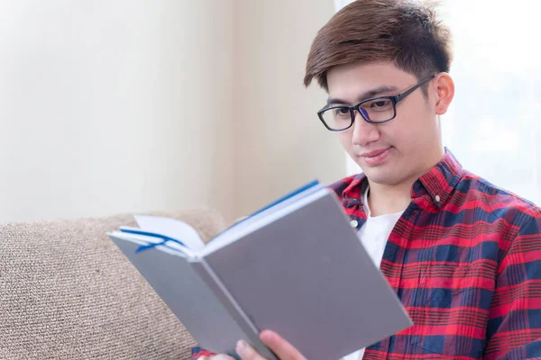 Joven Con Anteojos Sentados Sofá Sonríe Con Alegría Mirando Libro — Foto de Stock