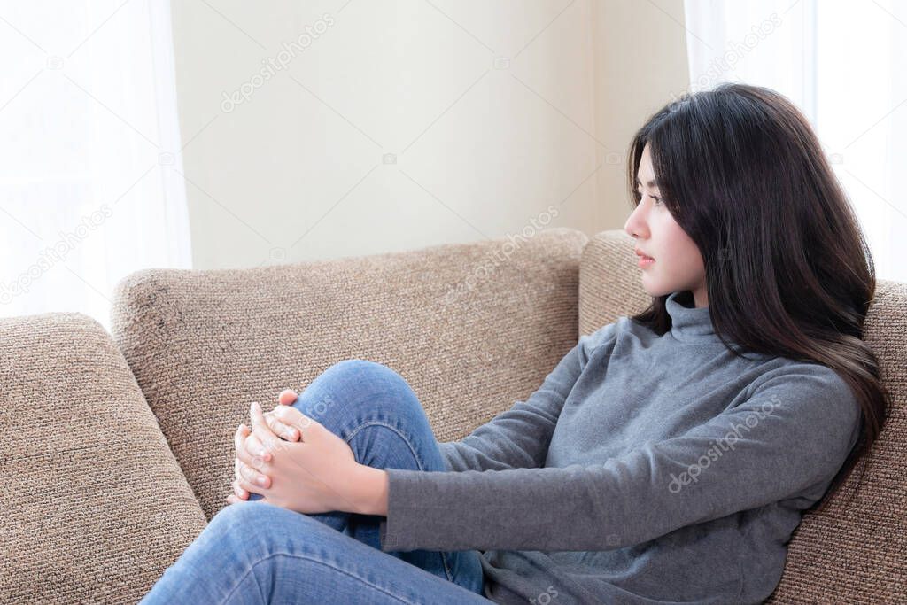 Close up face of unhappy Asian pretty young woman siting alone on couch with feeling sadness , emotional young woman was depressed on sofa