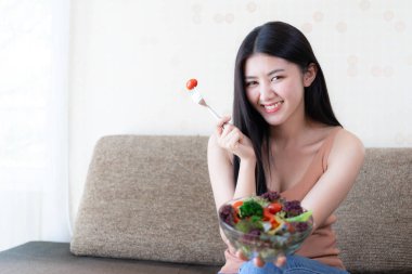 Hayat tarzı güzel güzel bir kadın Asyalı tatlı bir kız diyet yemeğinden zevk alıyor. Sabahları sağlıklı olmak için taze salata ve portakal suyu yiyor.
