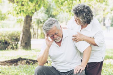 Ormanda acı çeken son sınıf Asyalı erkek bahçe parkında baş ağrısı, koca destekleyen eş yaşlı Asyalı yaşlı adam baş ağrısı konsepti. 