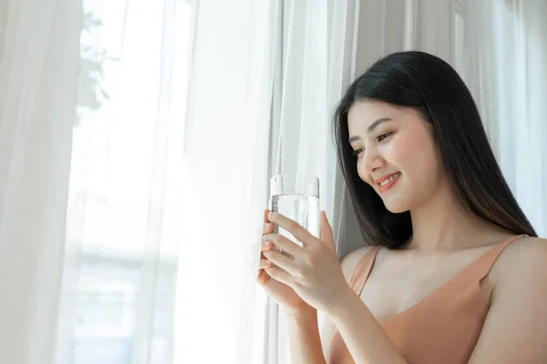 美しい美しさの女性アジアのかわいい女の子は幸せな飲酒を感じる朝の健康のためのきれいな飲料水 彼女の家の白い寝室の背景で時間を楽しんで ライフスタイルの美しさの女性のコンセプト — ストック写真