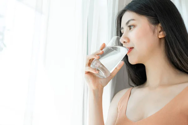 美しい美しさの女性アジアのかわいい女の子は幸せな飲酒を感じる朝の健康のためのきれいな飲料水 彼女の家の白い寝室の背景で時間を楽しんで ライフスタイルの美しさの女性のコンセプト — ストック写真