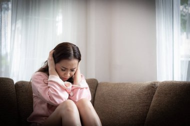 Evdeki kanepede umutsuzluk içindeki üzgün kadın.