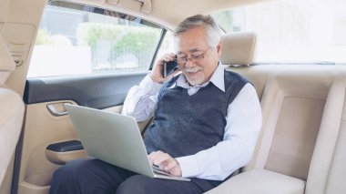 Son sınıf zengin hisse senedi tüccarı dizüstü bilgisayarla çalışıyor ve arabasında akıllı bir telefon kullanıyor. Son sınıf iş başarısı kavramı. 