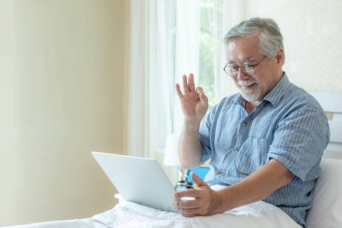 Dizüstü bilgisayar kullanan yaşlı bir erkek akrabalarına telefon eder torun torunu, gülümseyerek evde mutlu olur - son sınıf yaşam tarzı konsepti