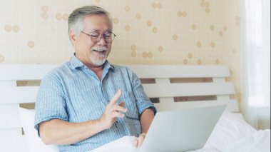 Dizüstü bilgisayar kullanan yaşlı bir erkek akrabalarına telefon eder torun torunu, gülümseyerek evde mutlu olur - son sınıf yaşam tarzı konsepti