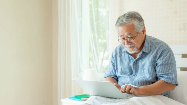 Son sınıf öğrencisi dizüstü bilgisayar kullanıyor. Gülümsüyor. Evde yatakta mutlu hissediyor.