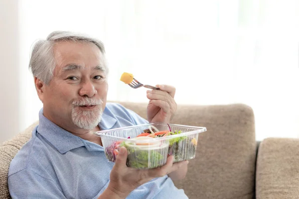 노인은 소파에서 샐러드를 먹는다 — 스톡 사진