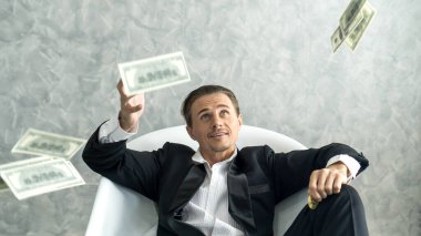 Mutlu iş adamı çok zengin bir adam yağmur parası gibi dolarları havaya fırlatır ve küvete Amerikan dolarını yatırır - iş başarısı konsepti