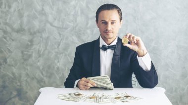 İş adamı zengini tüccar Bitcoin altın sikkesi tutuyor Bitcoin tüccarı için yeni para değişimi ve masa başı iş konsepti üzerine Amerikan doları banknotları